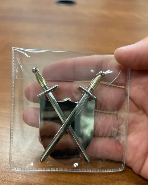 The back of the squadron coin, showing the crossed swords, in its clear pouch